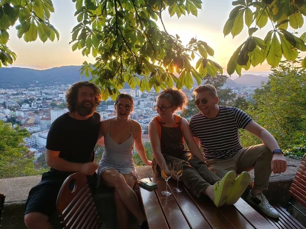 Travellers sitting on a bench at a viewpoint above an Austrian city