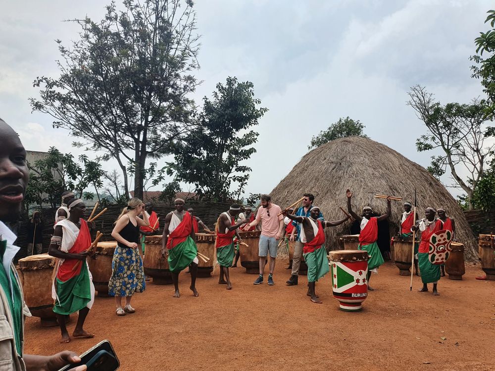 Drummers in red and green robes performing outside a thatched hut in Burundi