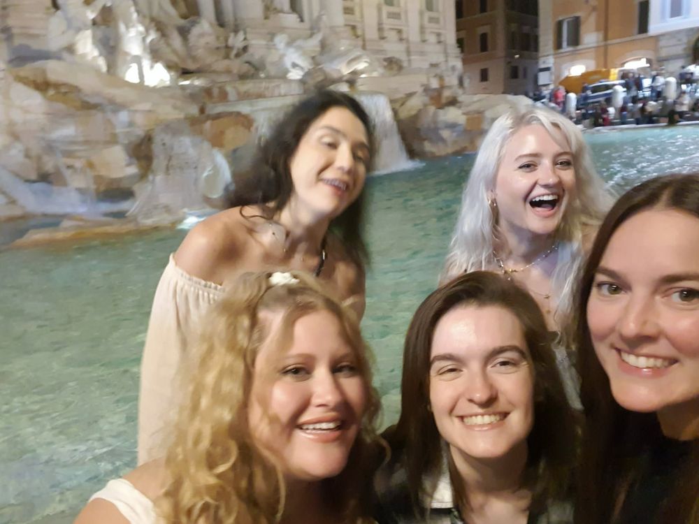 Four travellers taking a photo together at the Trevi Fountain in Rome