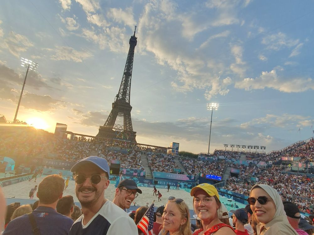 The group in a stadium crowd with the Eiffel Tower behind at sunset