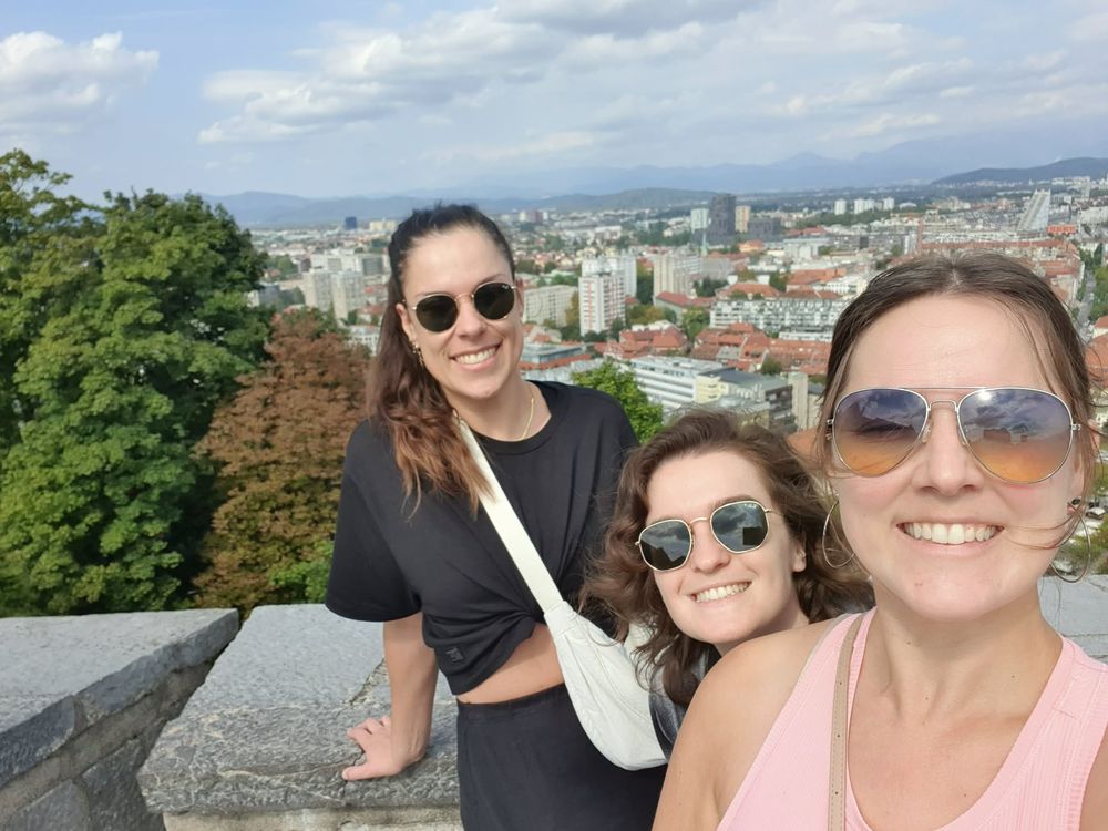 Three travellers on a viewpoint above the rooftops of a Slovenian city