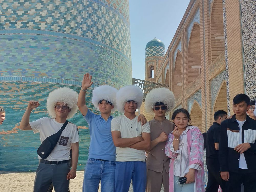 The group in traditional white hats in front of tiled architecture in Uzbekistan